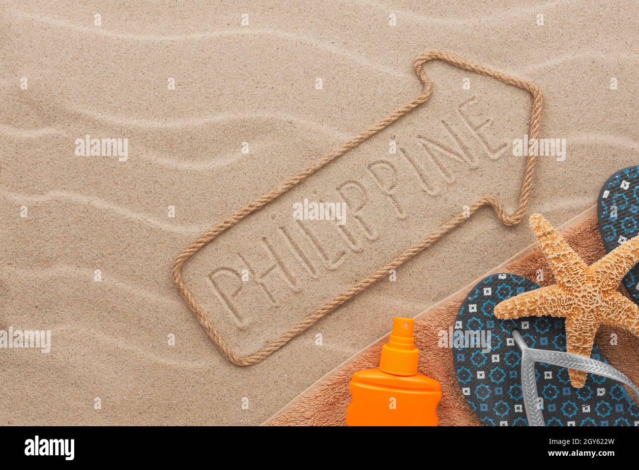 Philippines pointer and beach accessories lying on the sand, as background Stock Photo