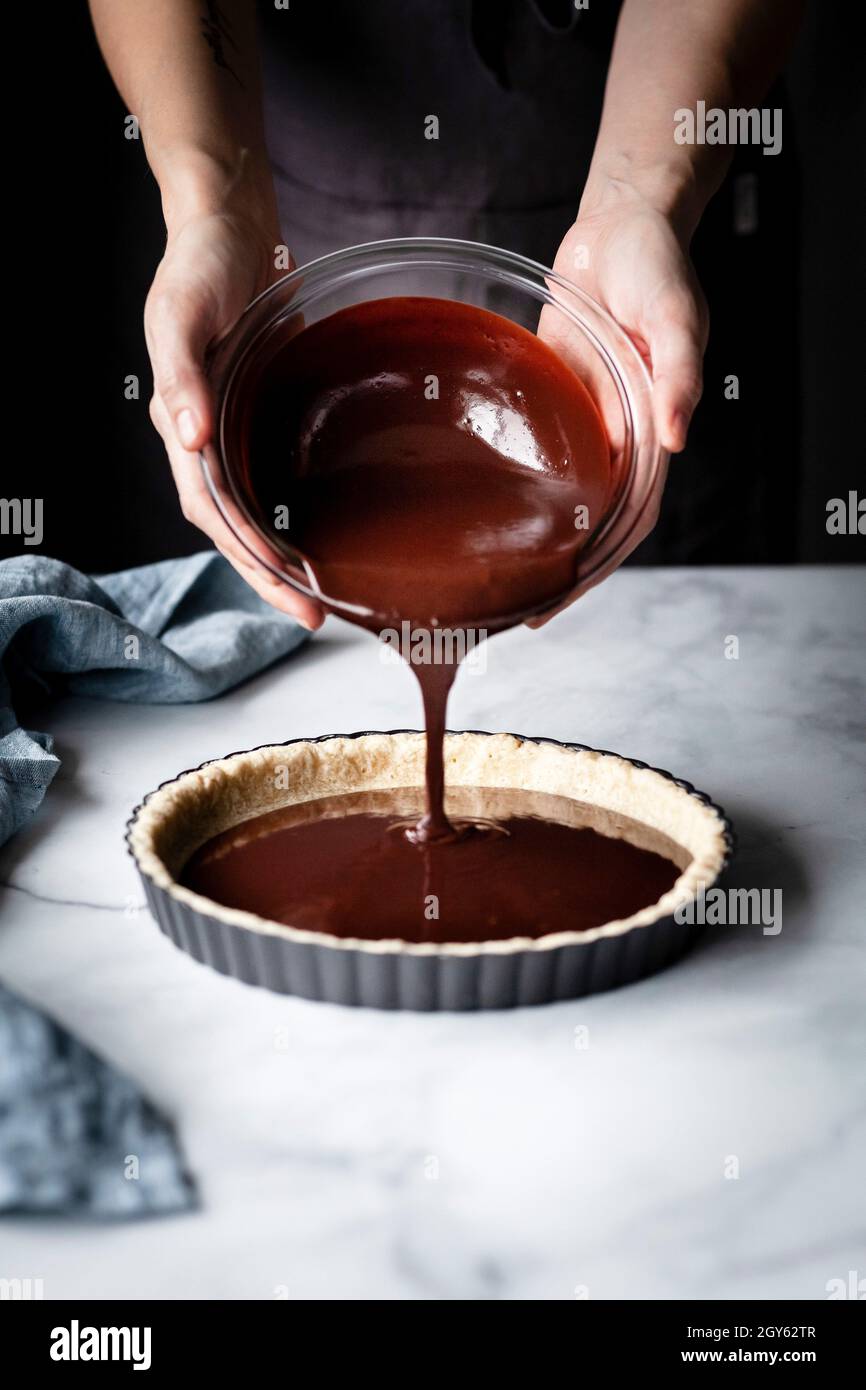 A baker pouring melted chocolate ganache into a tart shell Stock Photo Alamy