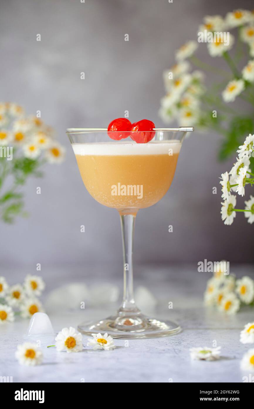 An Amaretto sour cocktail garnished with egg white foam and cocktail