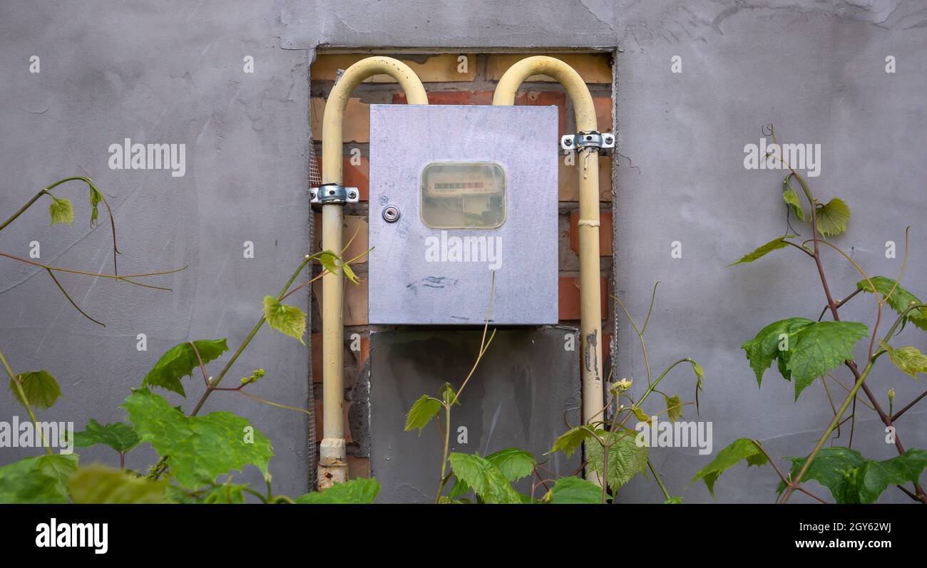 Natural gas meter with yellow pipes measuring gas consumption. An external gas meter in a private house for the distribution of domestic gas Stock Photo