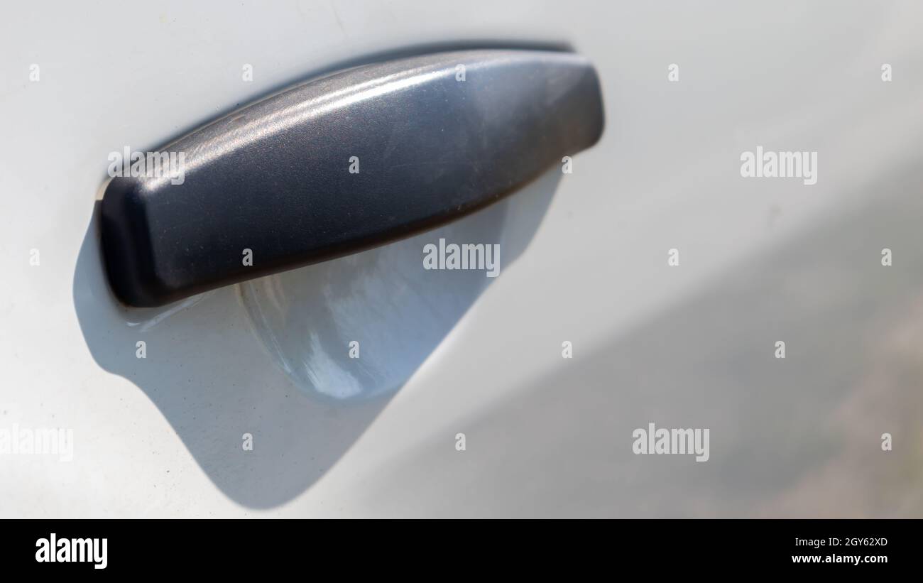 Black plastic door handle of a modern white car. Transport. Detail and