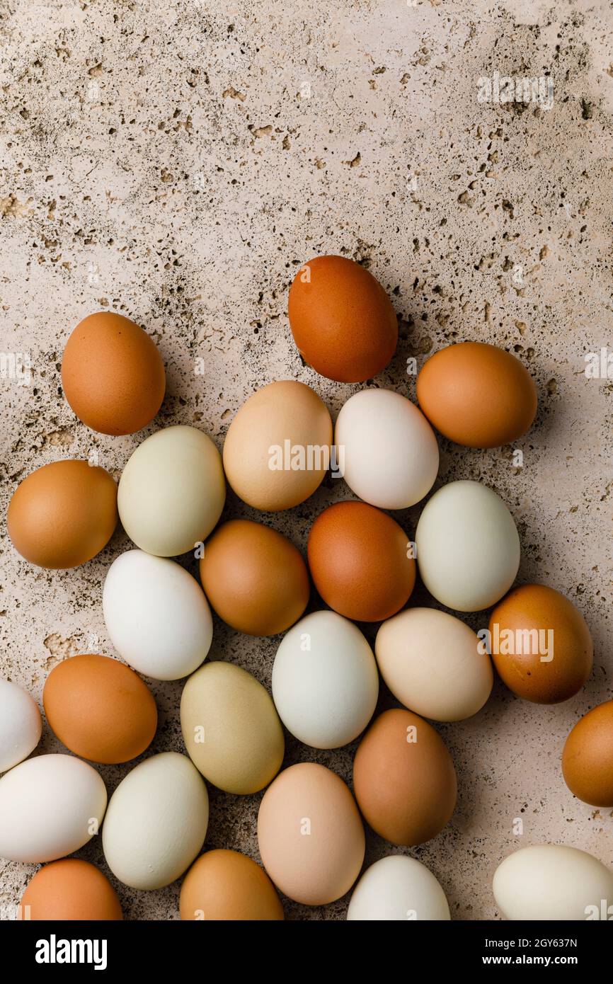 Multicolored raw farm eggs on beige stone background Stock Photo