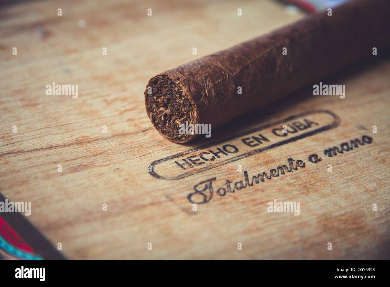 Brown cuban cigar on vintage wooden box with inscription in spanish