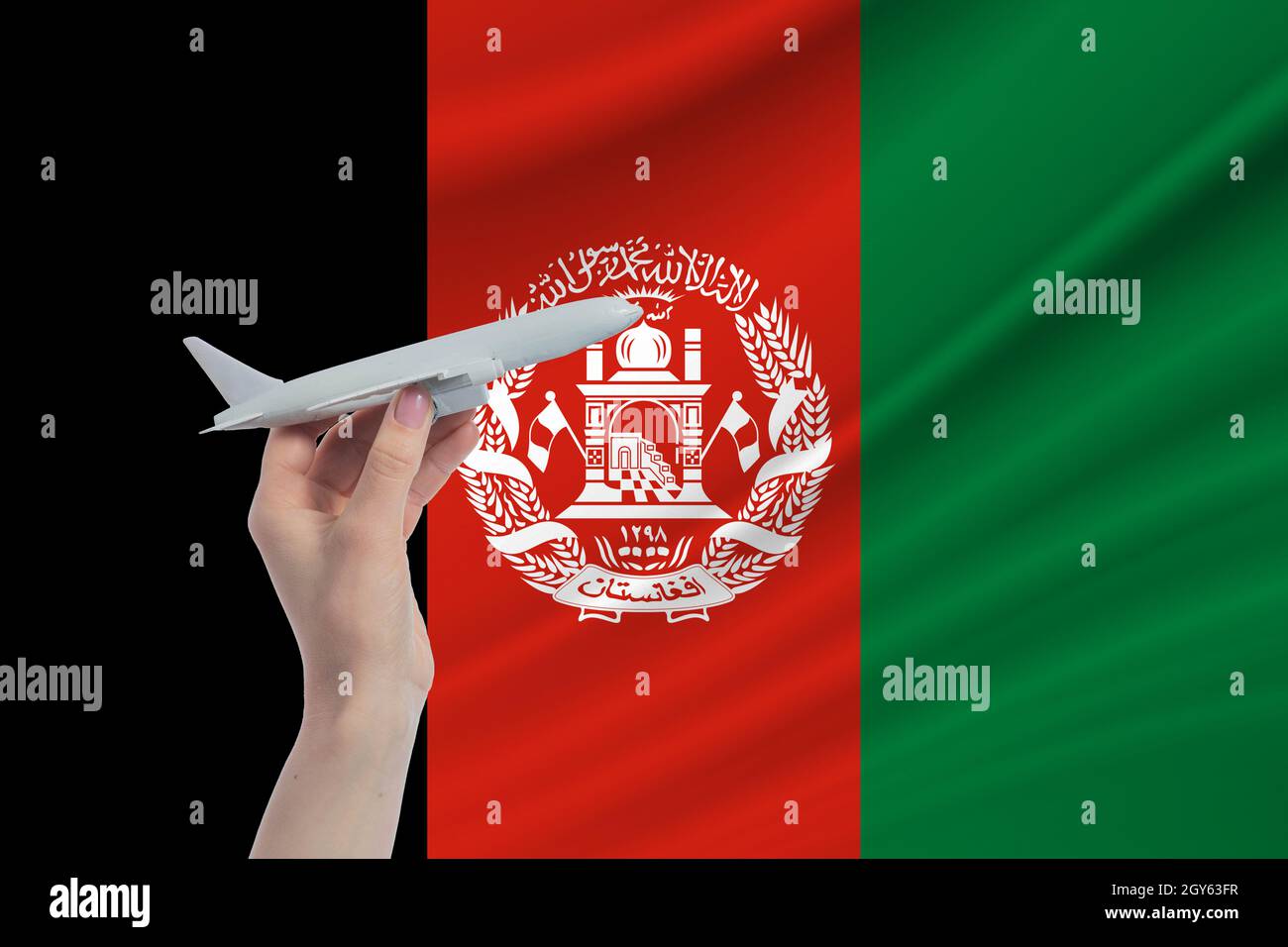 Airplane in hand with national flag of Afghanistan. Travel to Afghanistan. Stock Photo