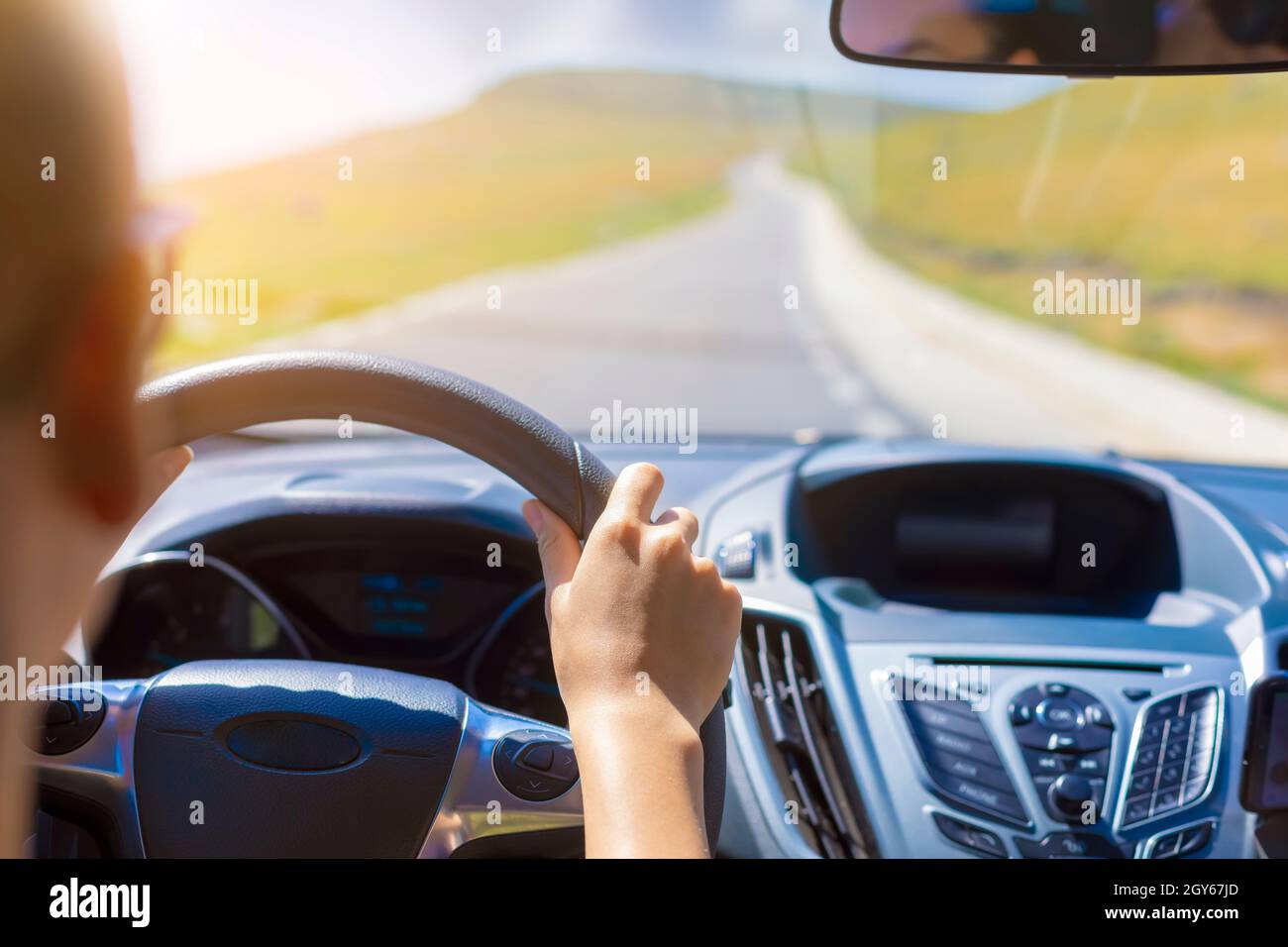 Girl hands on the steering wheel of a car while driving. Against the