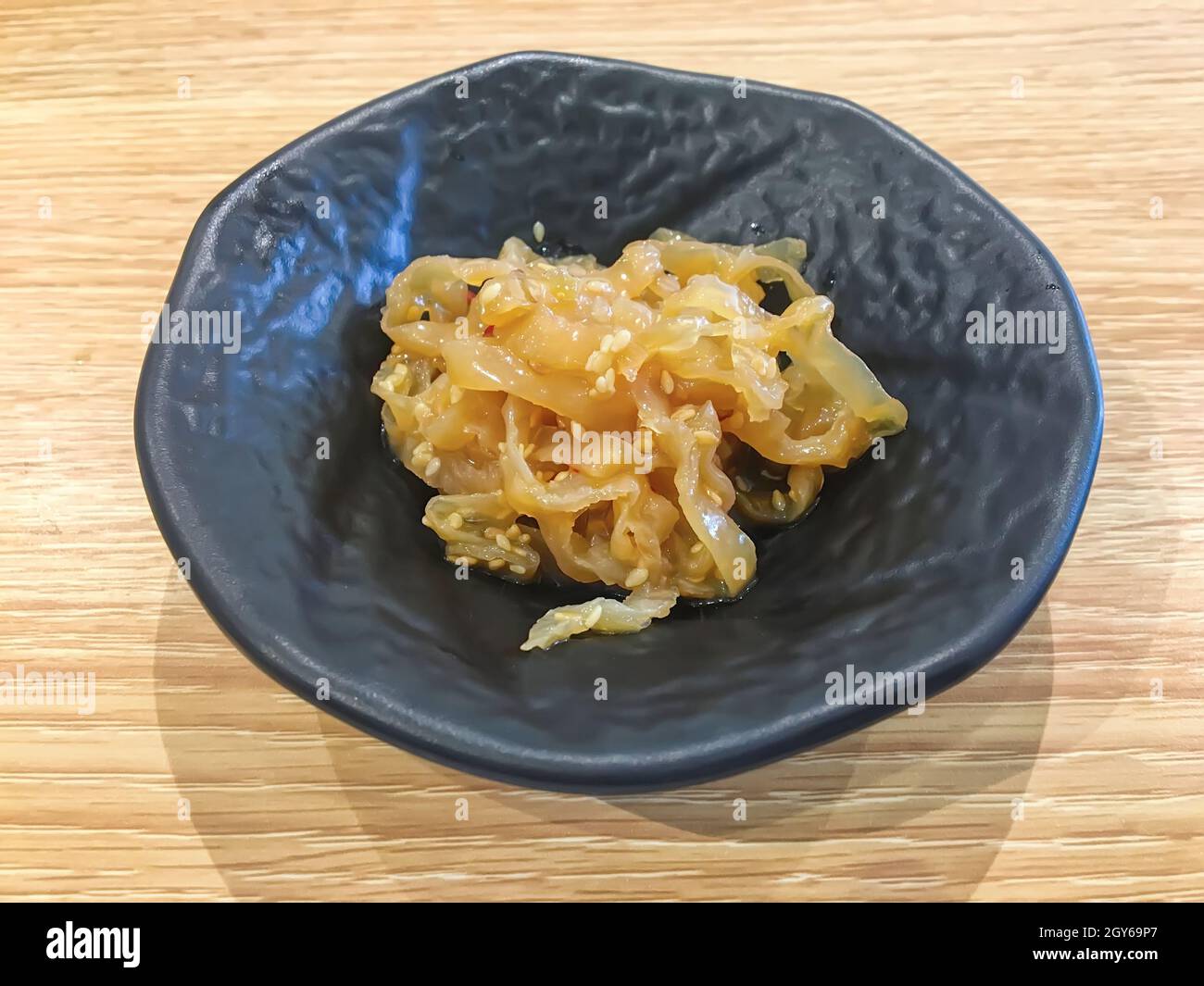 Jellyfish salad in black plate on the wood table. Stock Photo