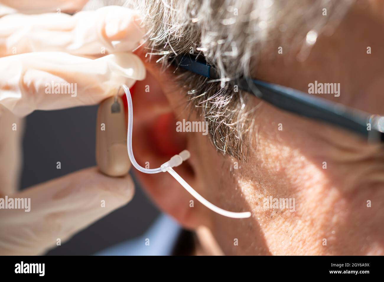 Doctor Inserting Hearing Aid In The Ear Of Man Stock Photo - Alamy