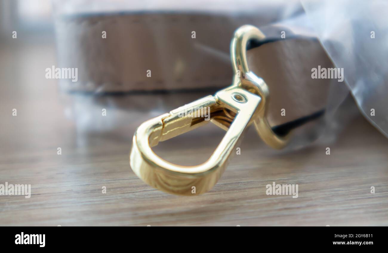 https://c8.alamy.com/comp/2GY6B11/swivel-snap-fastener-with-leather-beige-bag-strap-on-a-wooden-background-metal-carabiner-with-swivel-clip-or-hook-small-gold-fittings-close-up-in-se-2GY6B11.jpg