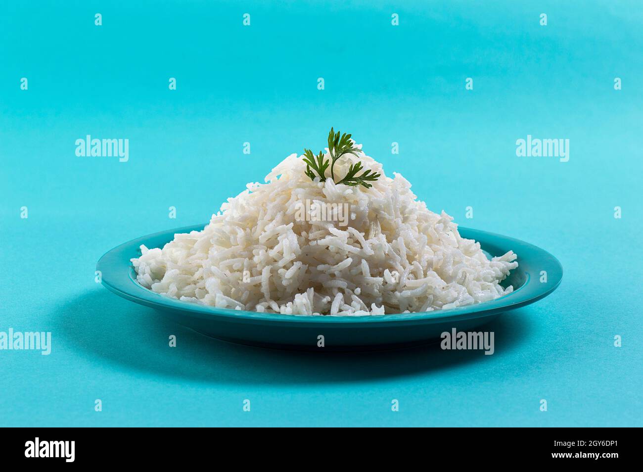 Cooked plain white basmati rice with corriander in a blue plate on blue ...