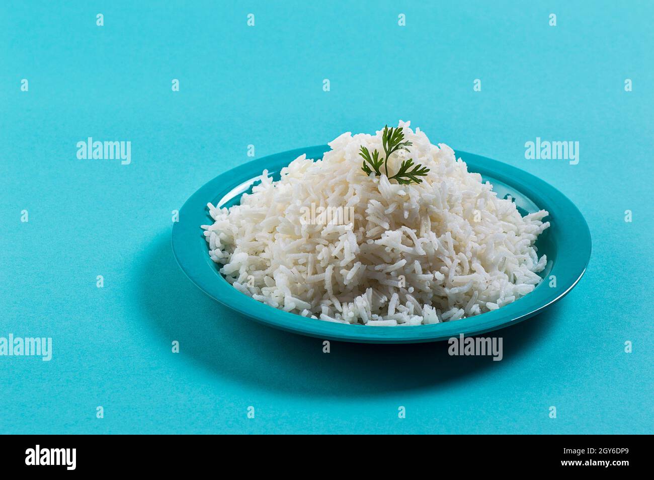 Cooked plain white basmati rice with corriander in a blue plate on blue