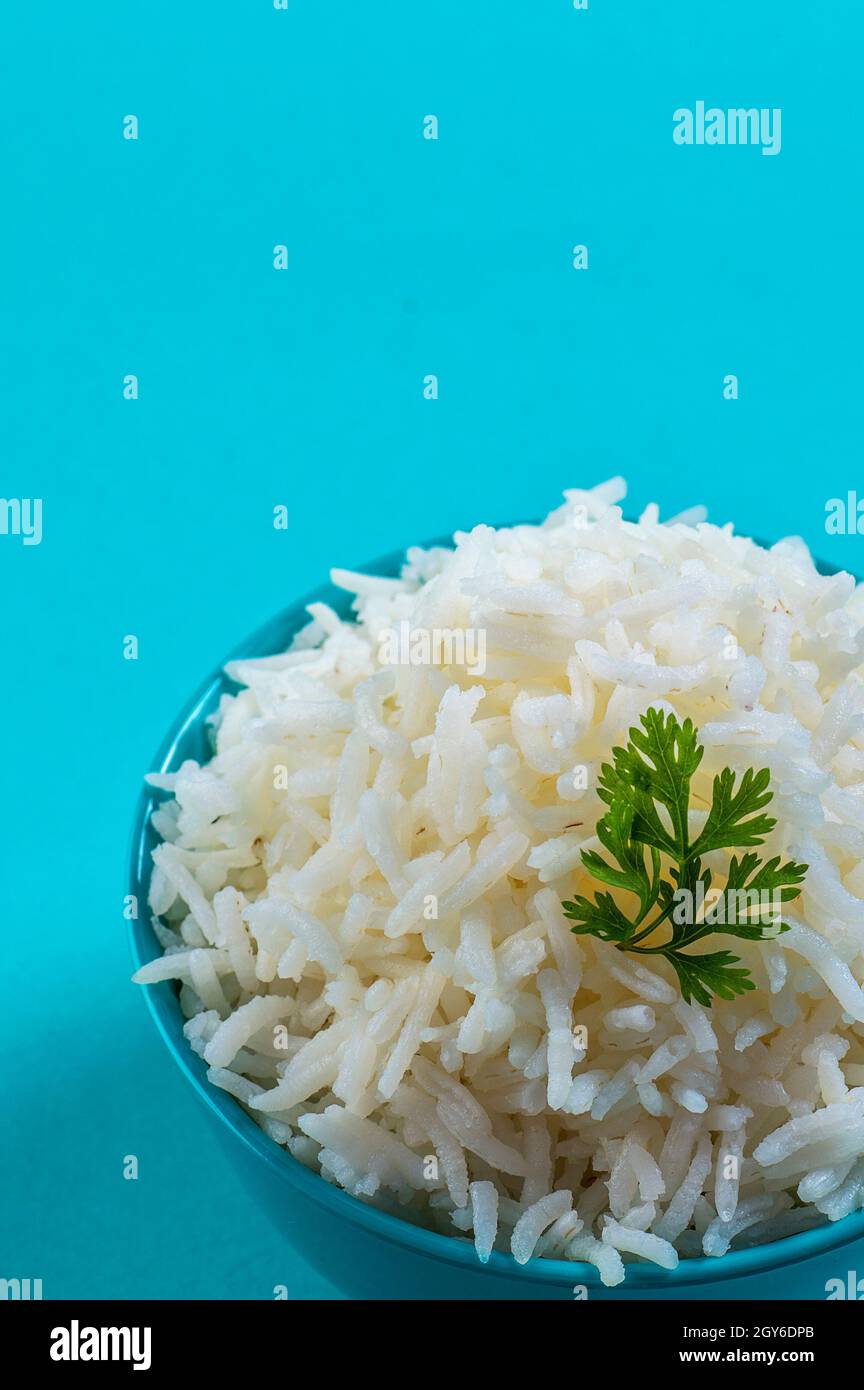 Cooked plain white basmati rice with corriander in a blue bowl on blue