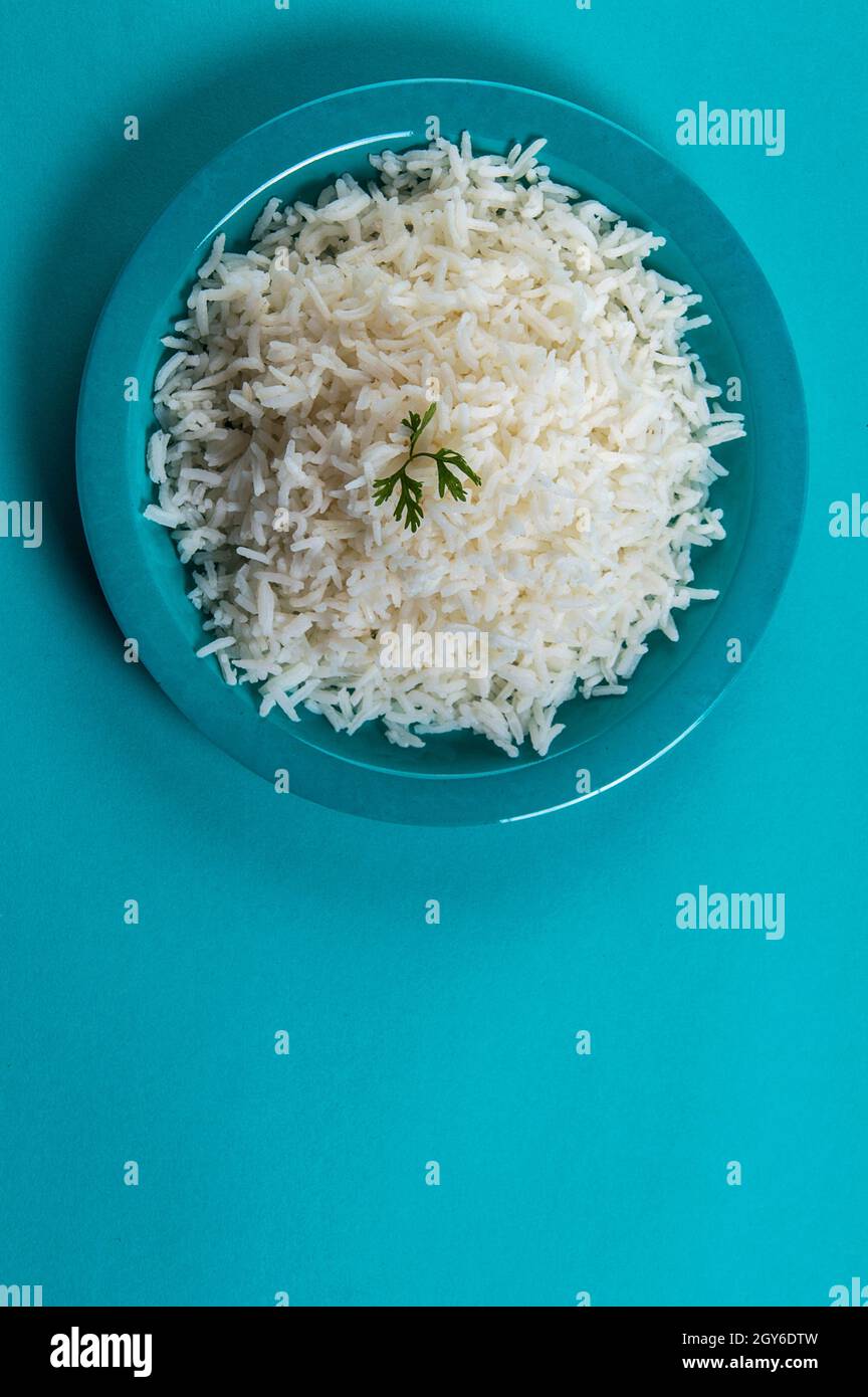 Cooked plain white basmati rice with corriander in a blue plate on blue