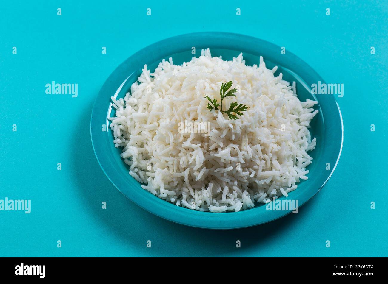 Cooked plain white basmati rice with corriander in a blue plate on blue