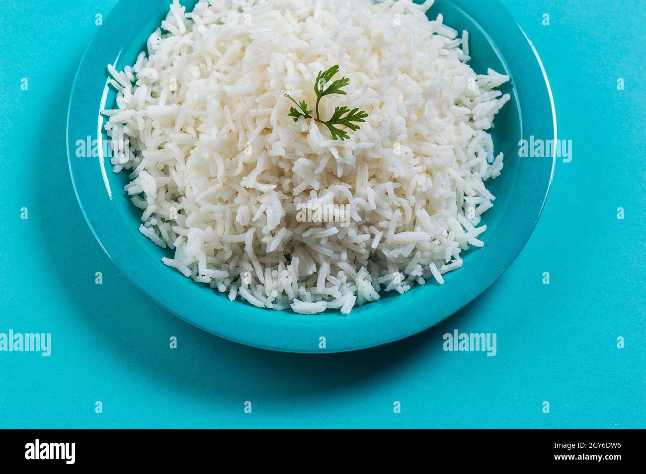 Cooked plain white basmati rice with corriander in a blue plate on blue