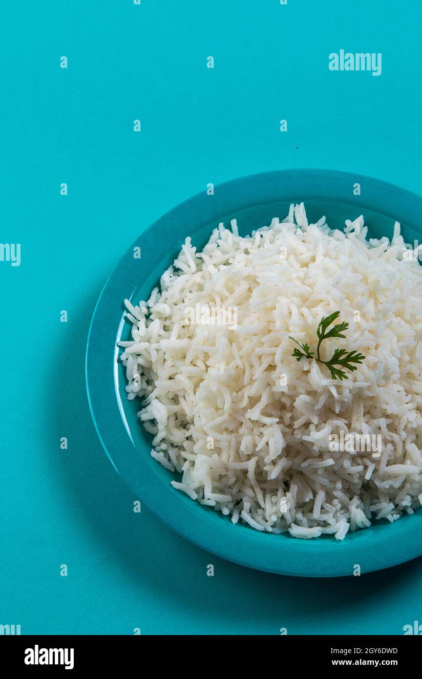 Cooked plain white basmati rice with corriander in a blue plate on blue