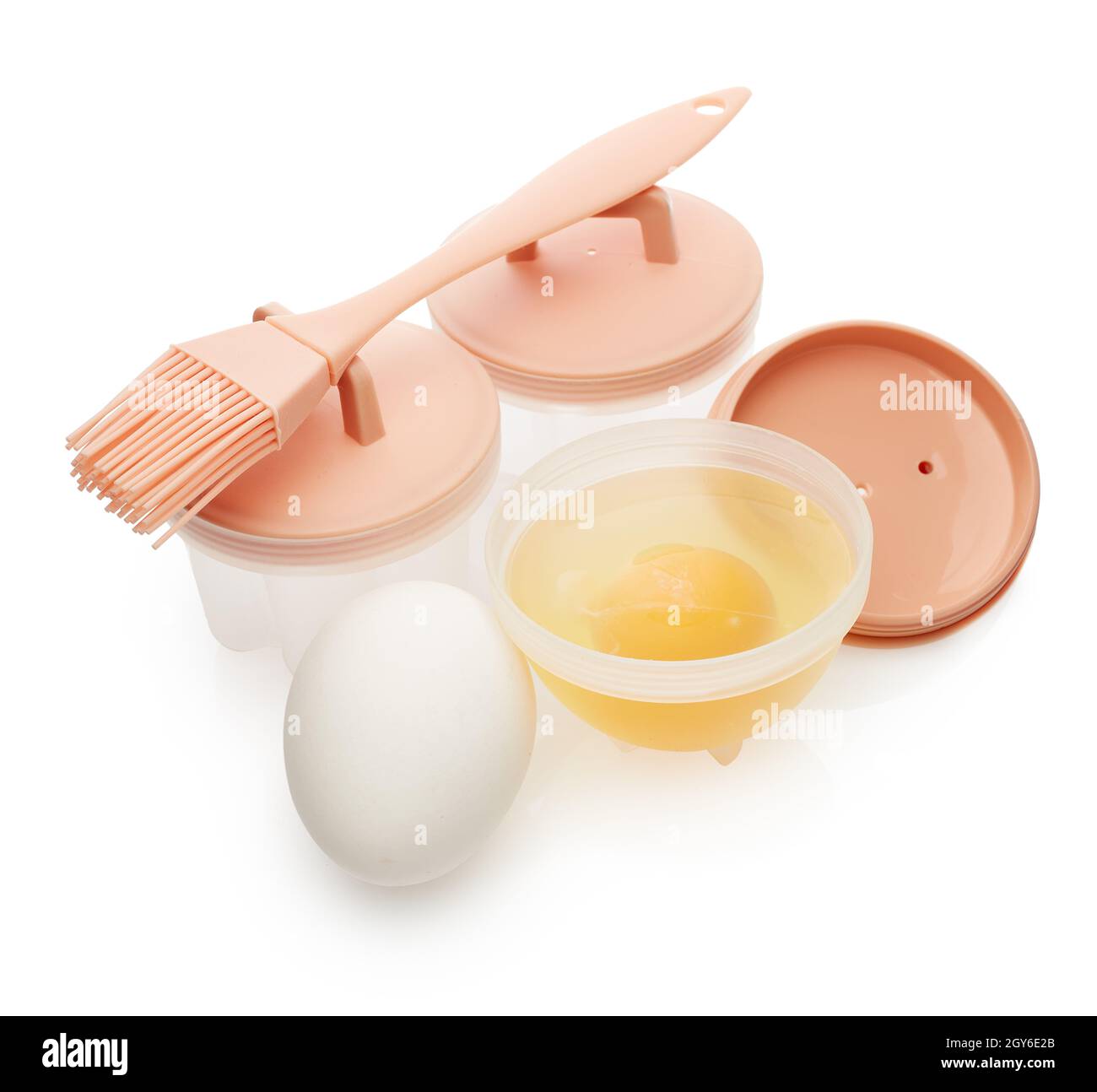 Set of heat resistant silicone molds for poached egg, basting brush and fresh raw eggs isolated on white background. Utensil for cooking. Poached egg. Stock Photo