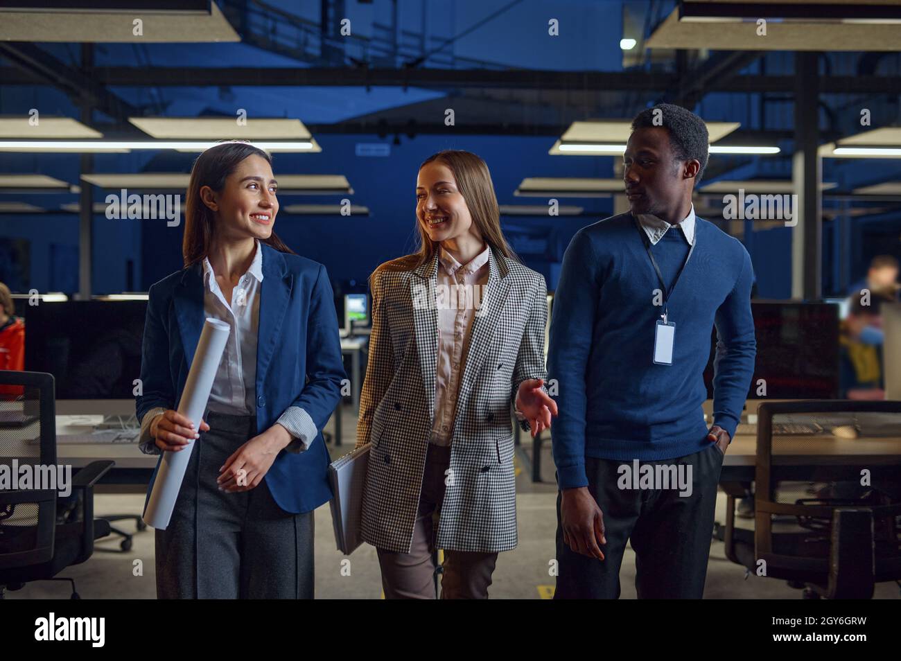 One man and two women in night office. Smiling male and female workers ...