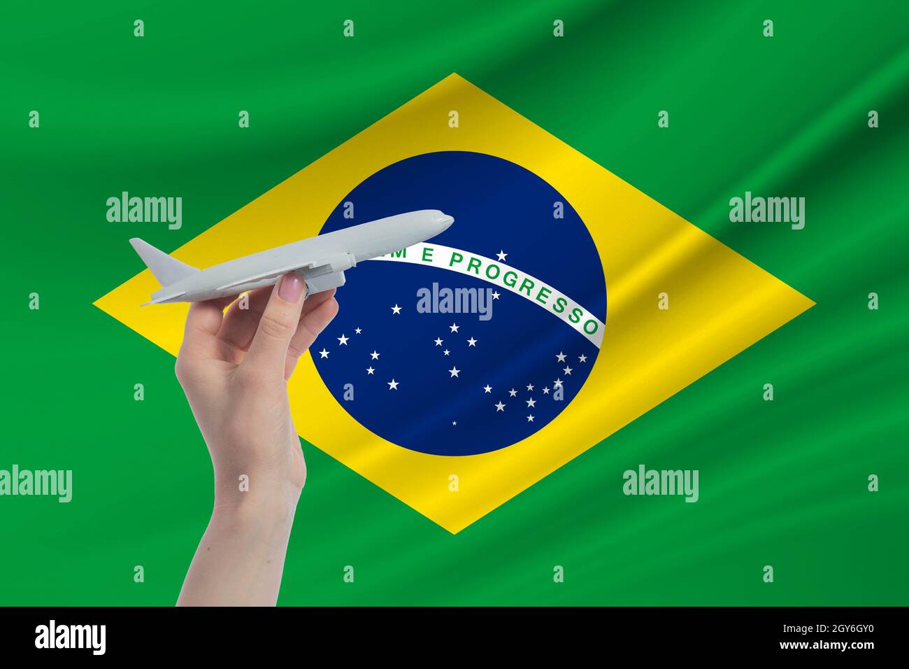 Airplane in hand with national flag of Brazil. Travel to Brazil. Stock Photo