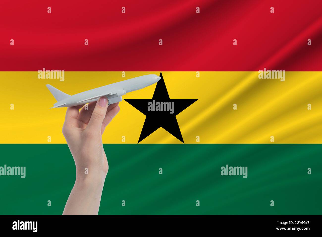 Airplane in hand with national flag of Ghana. Travel to Ghana Stock