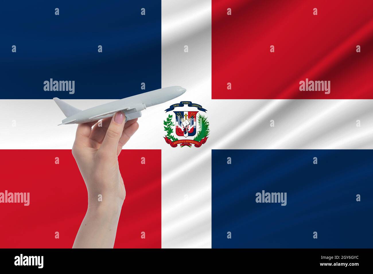 Airplane in hand with national flag of Dominican Republic Travel to Dominican Republic. Stock Photo