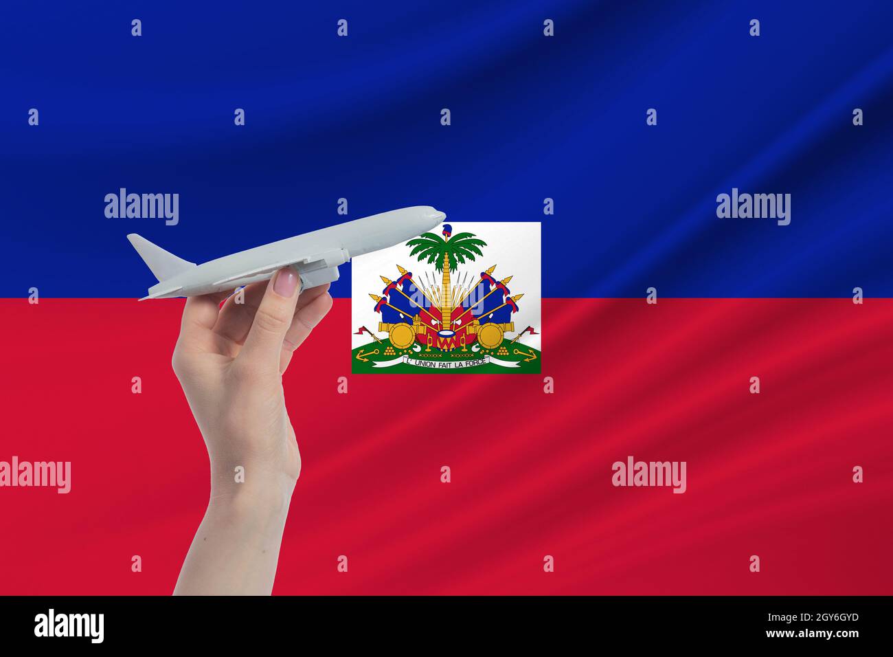 Airplane in hand with national flag of Haiti. Travel to Haiti. Stock Photo