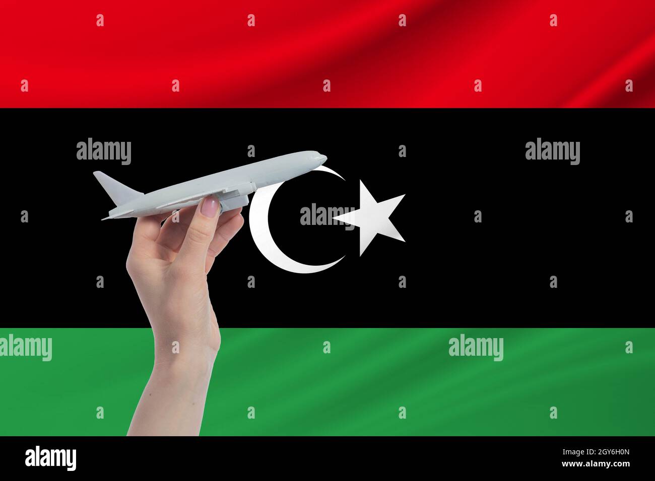 Airplane in hand with national flag of Libya. Travel to Libya. Stock Photo