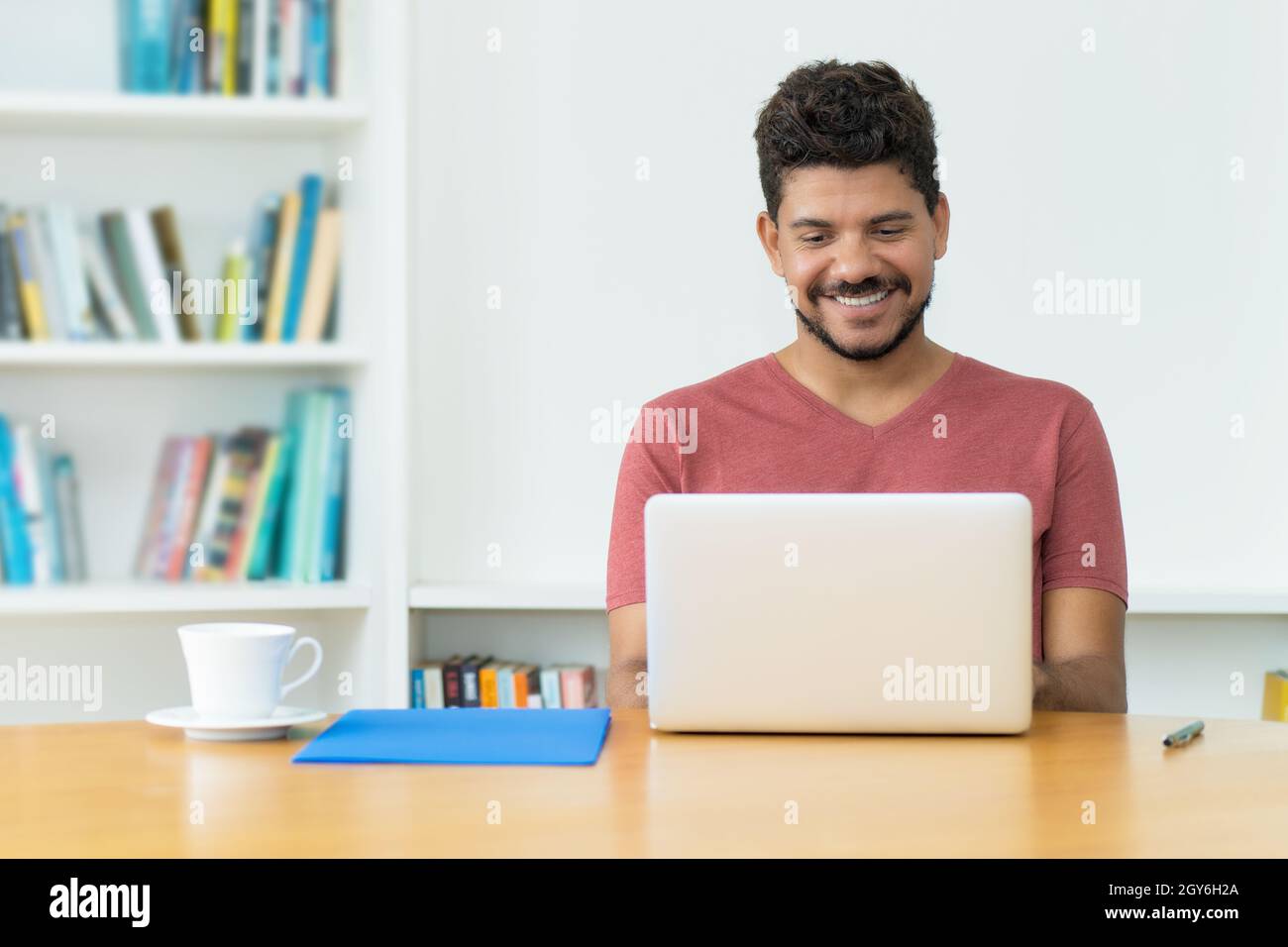 Hispanic mature man with beard at video call at computer indoors at home Stock Photo