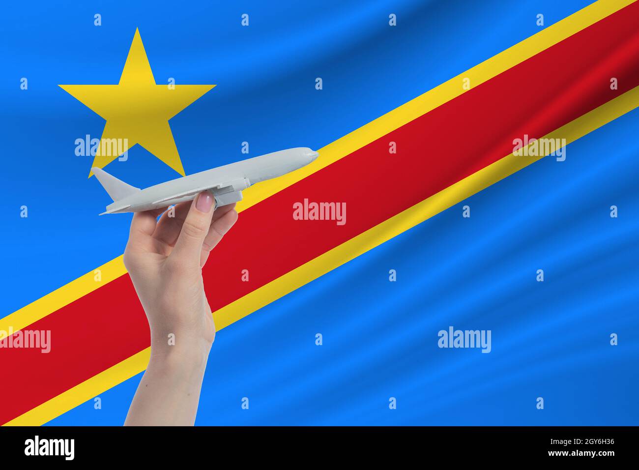 Airplane in hand with national flag of Democratic Republic of the Congo Travel to Democratic Republic of the Congo. Stock Photo