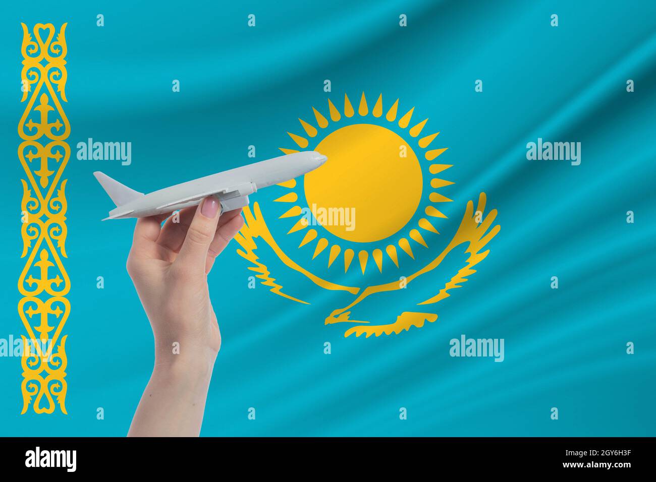 Airplane in hand with national flag of Kazakhstan Travel to Kazakhstan. Stock Photo