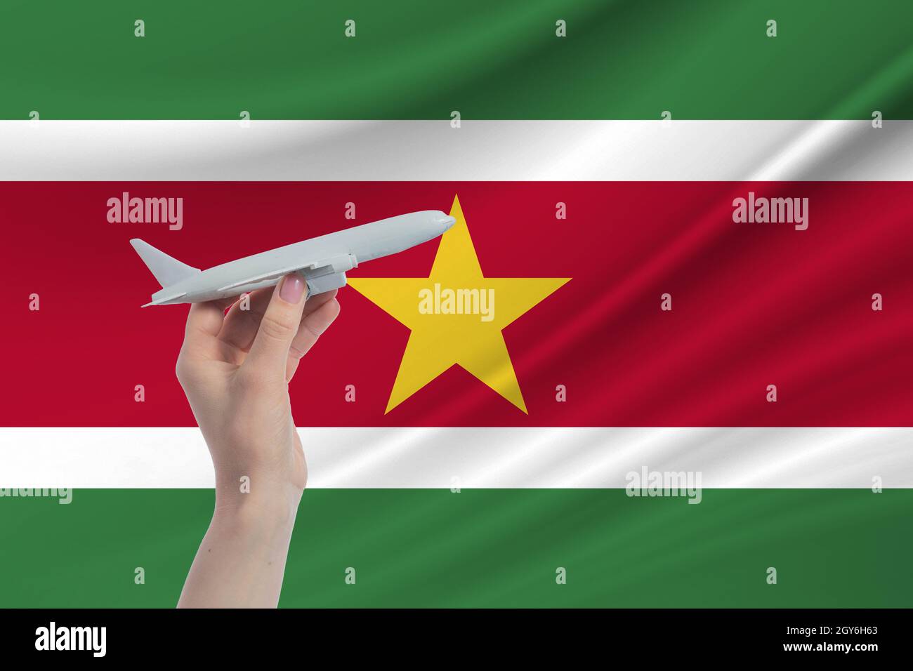 Airplane in hand with national flag of Suriname. Travel to Suriname. Stock Photo