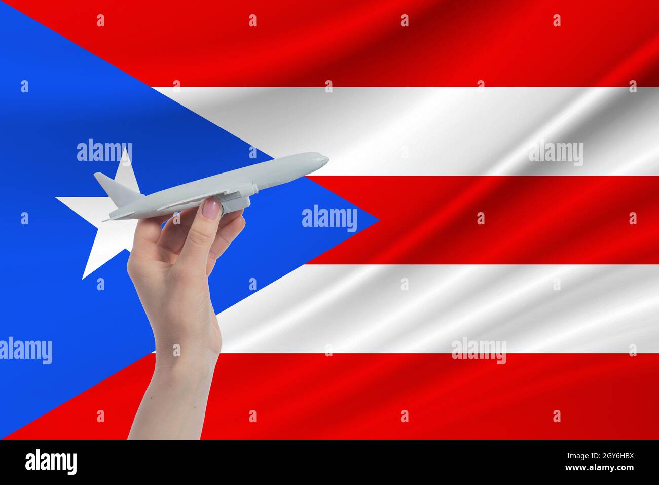 Airplane in hand with national flag of Puerto Rico. Travel to Puerto