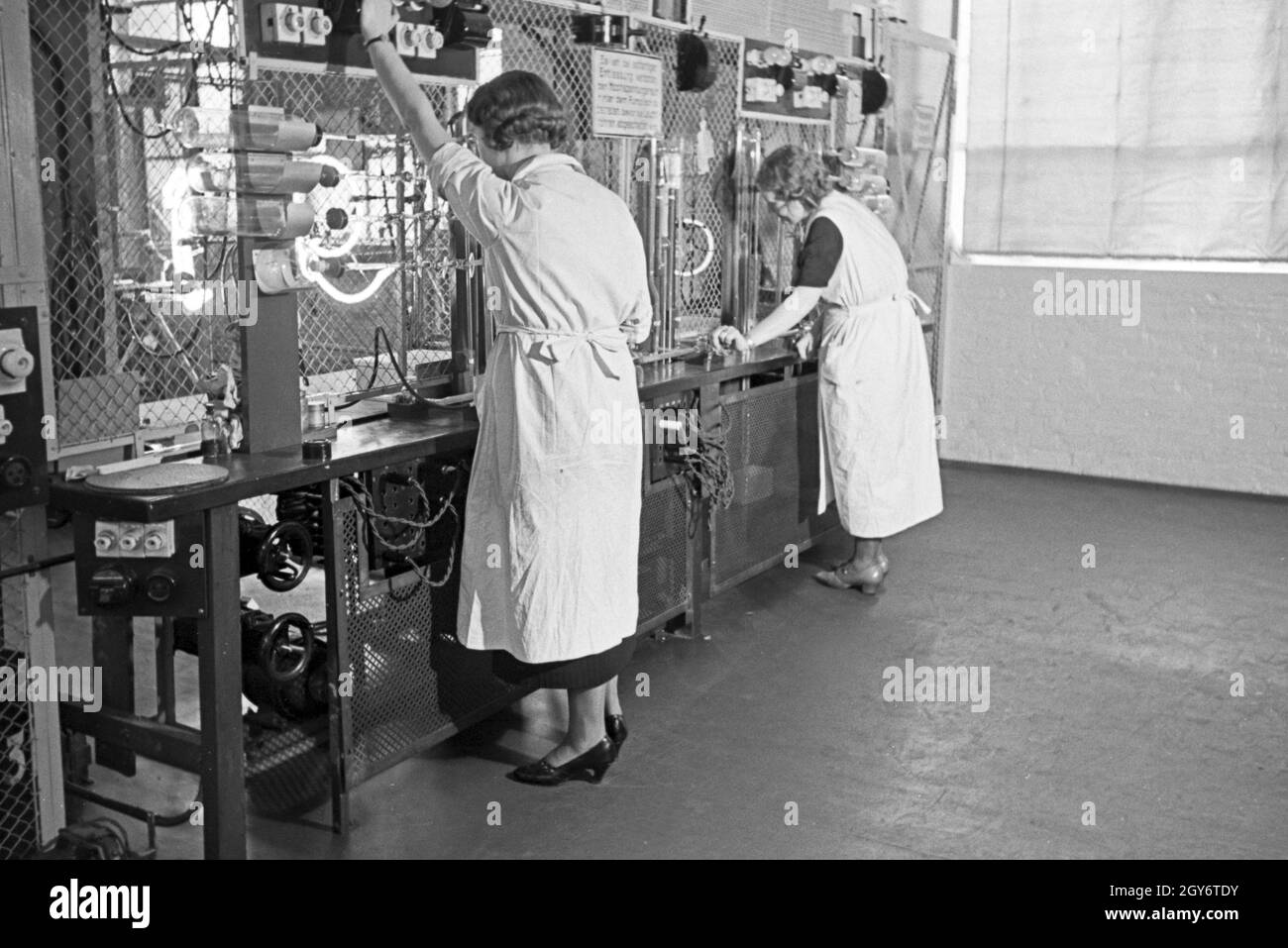 Mitarbeiterinnen bei der Produktion von Leuchtröhren, Deutschland 1930er Jahre. Female staff members producing fluorescent tubes, Germany 1930s. Stock Photo