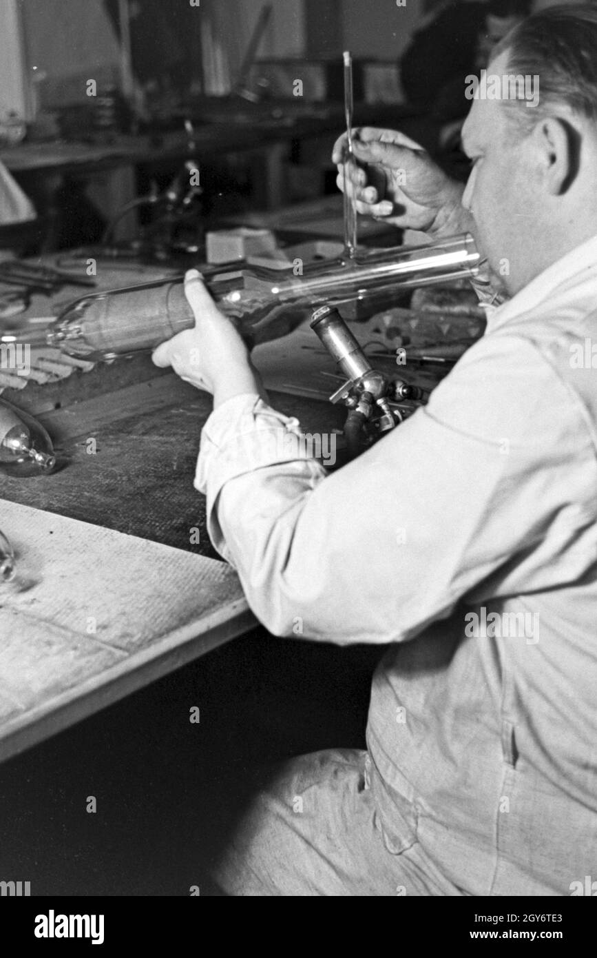 Ein Mitarbeiter einer Leuchtröhrenfabrik bei der Herstellung einer Leuchtöhre, Deutschland 1930er Jahre. A staff member producing a fluorescent tube, Germany 1930s. Stock Photo