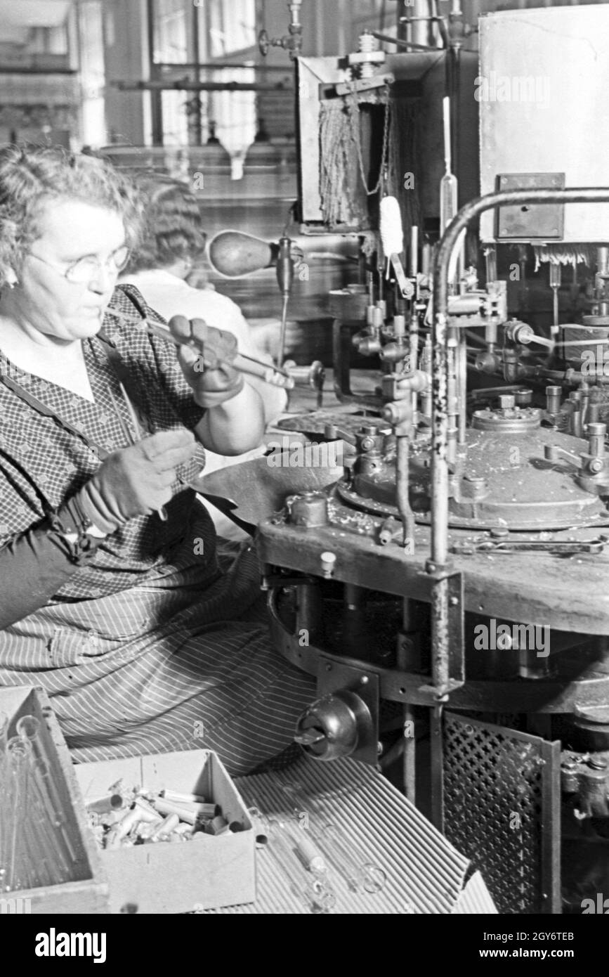 Eine Mitarbeiterin bei der Produktion von Leuchtröhren, Deutschland 1930er Jahre. A female staff memmber producing fluorescent tubes, Germany 1930s. Stock Photo