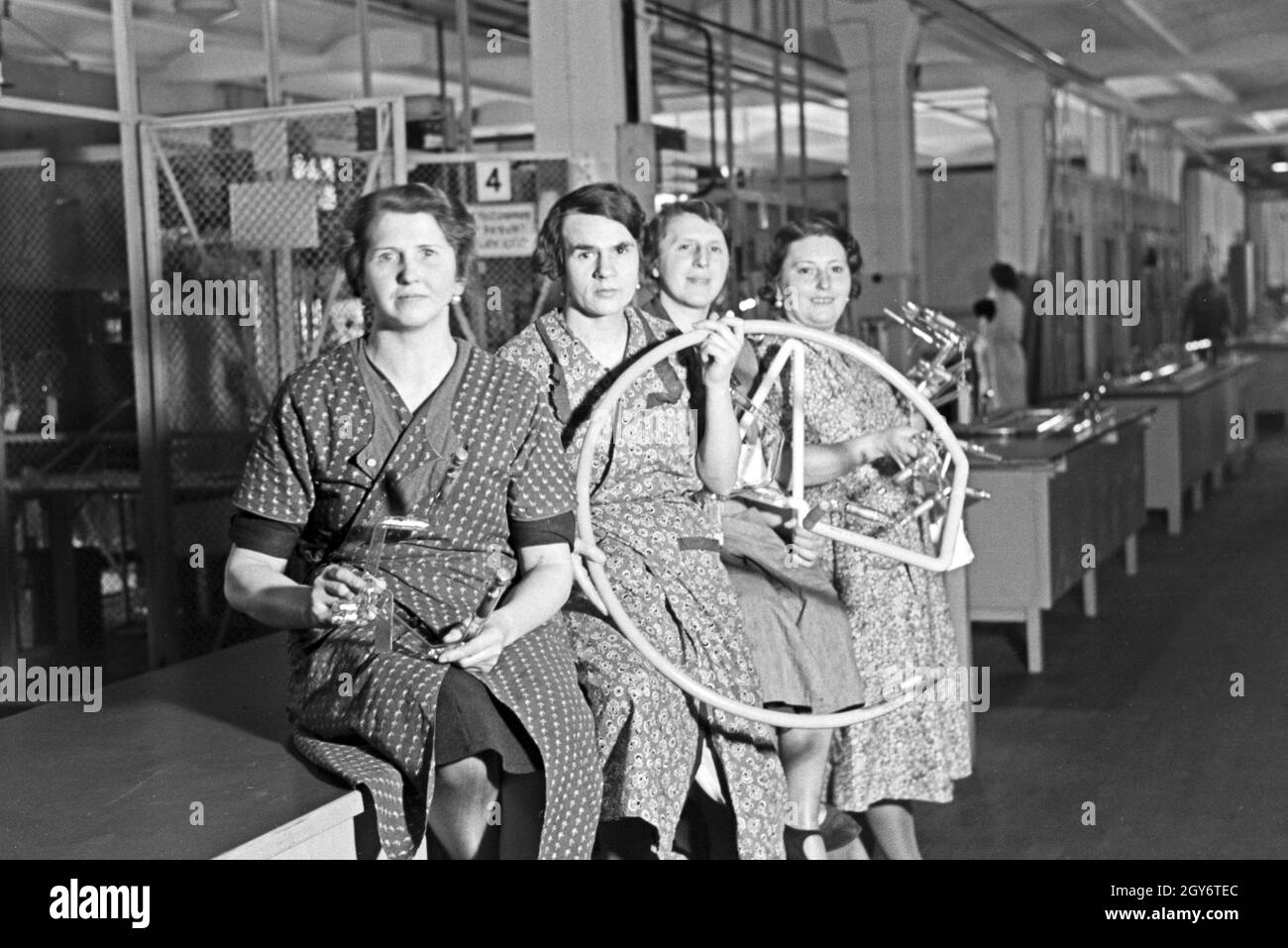 Mitarbeiterinnen einer Leuchtröhrenfabrik mit einem ihrer Produkte, Deutschland 1930er Jahre. Female staff members of a fluorescent tubes producing factory with one of their products, Germany 1930s. Stock Photo