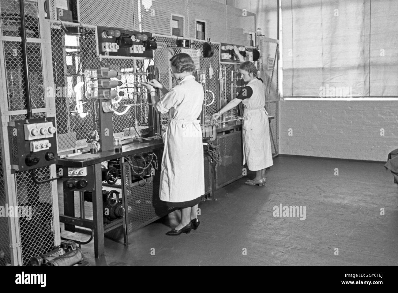Mitarbeiterinnen bei der Produktion von Leuchtröhren, Deutschland 1930er Jahre. Female staff members producing fluorescent tubes, Germany 1930s. Stock Photo