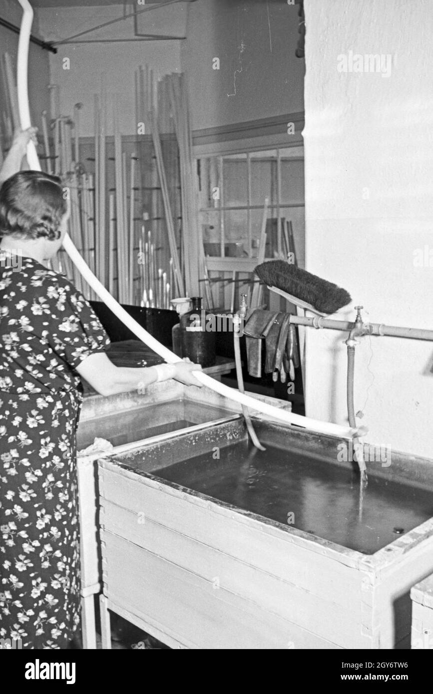Eine Mitarbeiterin bei der Reinigung von Leuchtröhren, Deutschland 1930er Jahre. A female staff member cleaning fluorescent tubes, Germany 1930s. Stock Photo