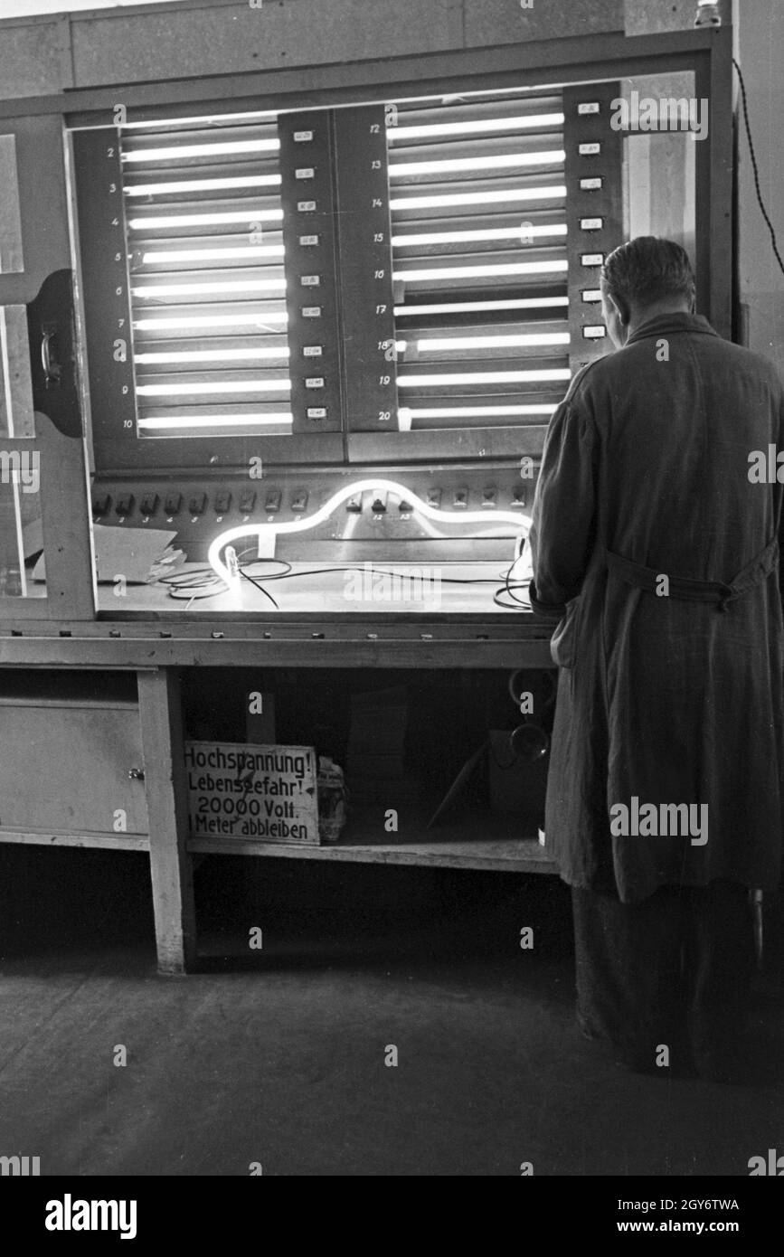 Ein Mitarbeiter testet fertige Leuchtröhren, Deutschland 1930er Jahre. A staff member testing fluorescent tubes, Germany 1930s. Stock Photo