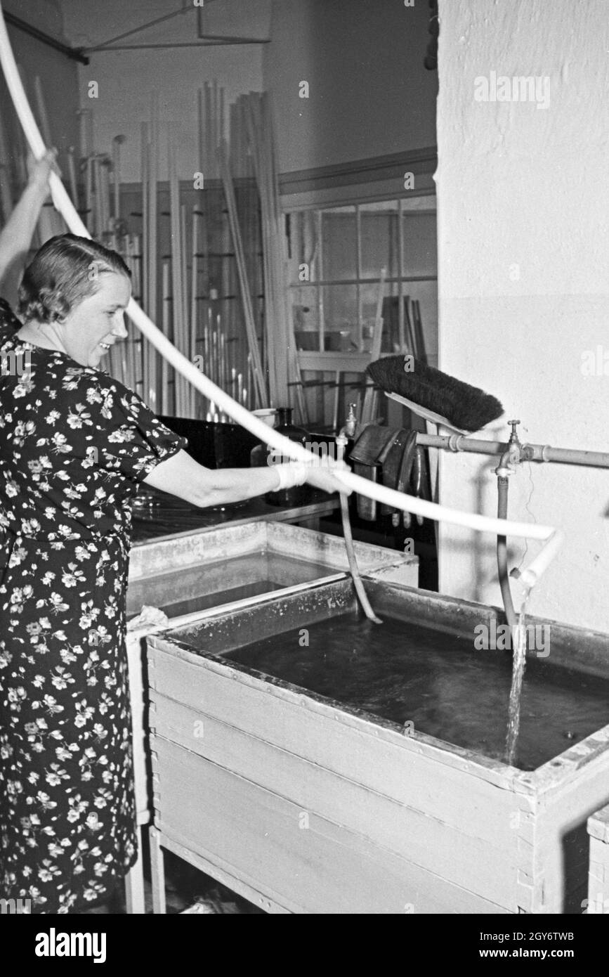 Eine Mitarbeiterin bei der Reinigung von Leuchtröhren, Deutschland 1930er Jahre. A female staff member cleaning fluorescent tubes, Germany 1930s. Stock Photo