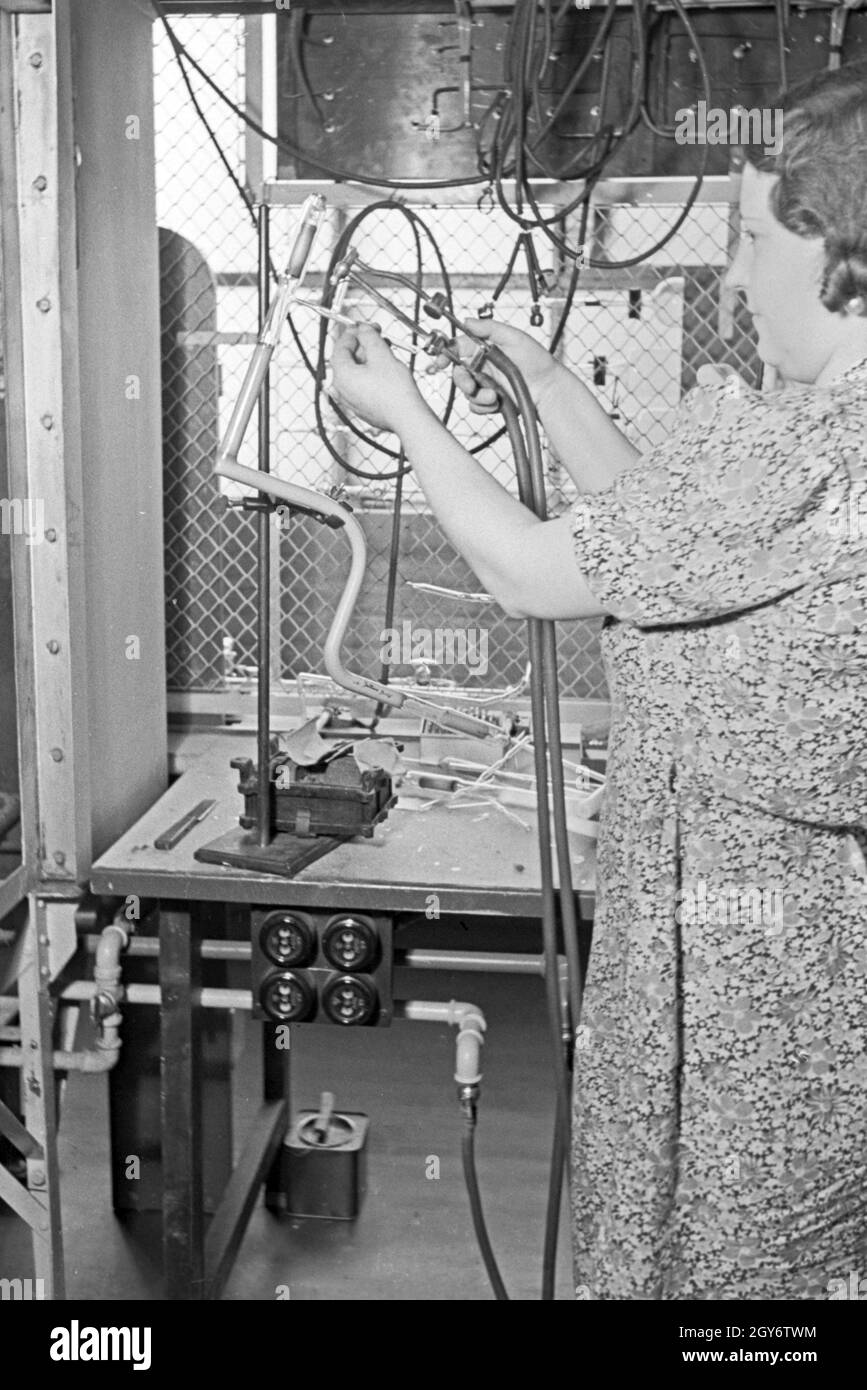 Eine Mitarbeiterin bei der Produktion von Leuchtröhren, Deutschland 1930er Jahre. A female staff memmber producing fluorescent tubes, Germany 1930s. Stock Photo