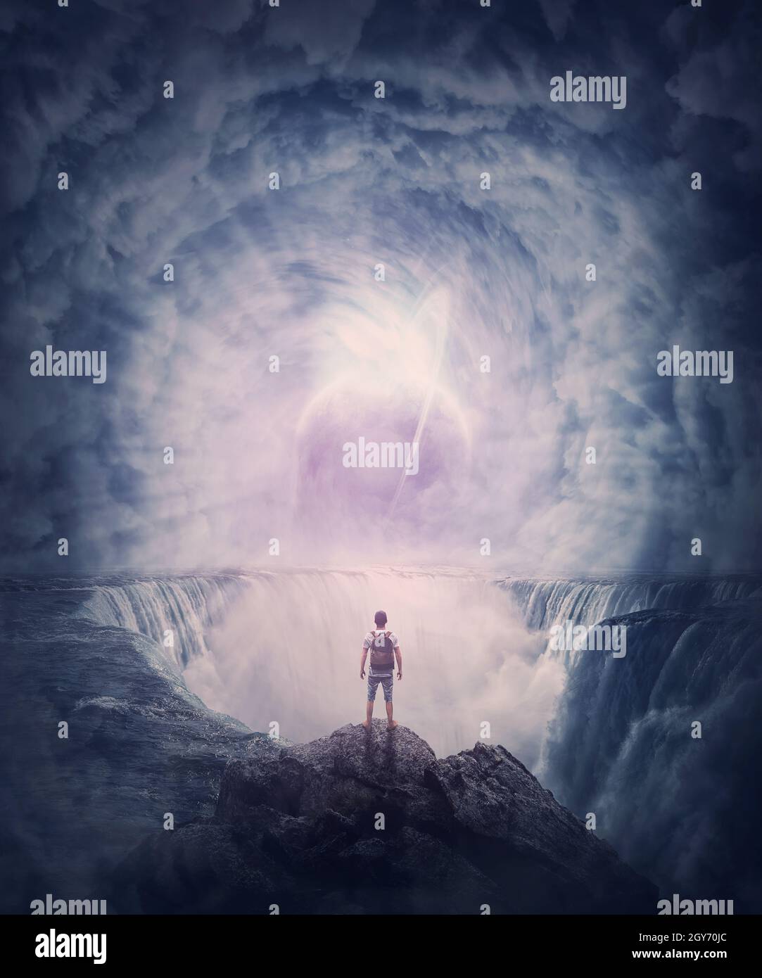 Person stands on the edge of a cliff above a waterfall looking at a huge whirlwind in the clouds that creates a portal to another planet. Surreal and Stock Photo