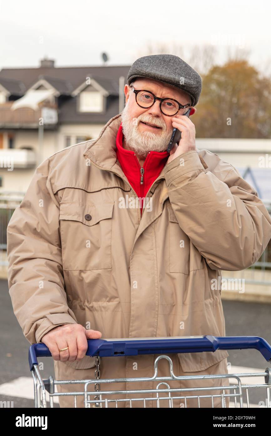 Senior with winter cloth using cell phone while he is pushing is ...