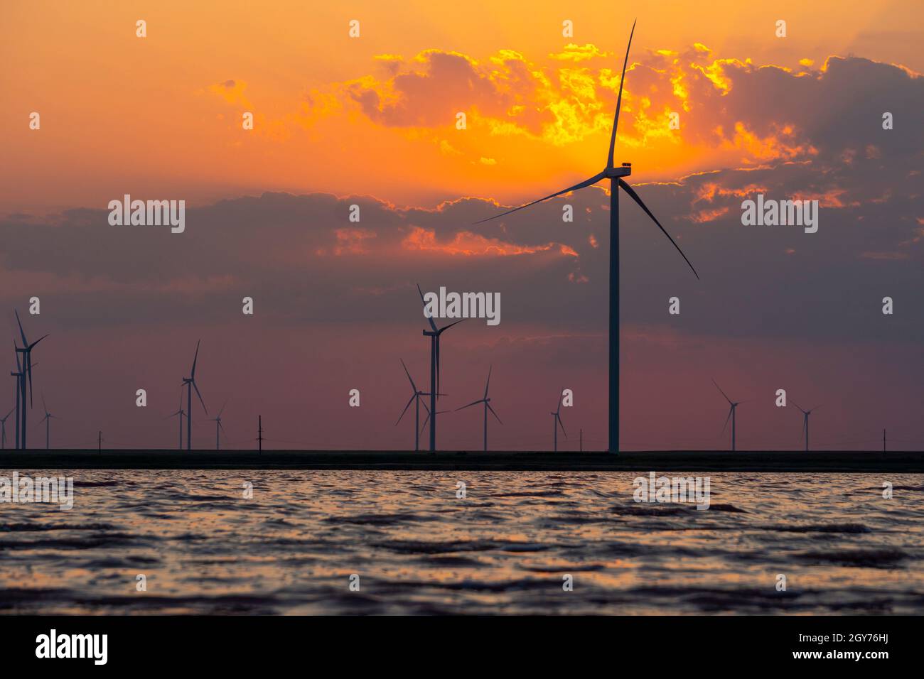 Silhouettes of wind turbines farm Behind the Lake at Sunset Stock Photo ...