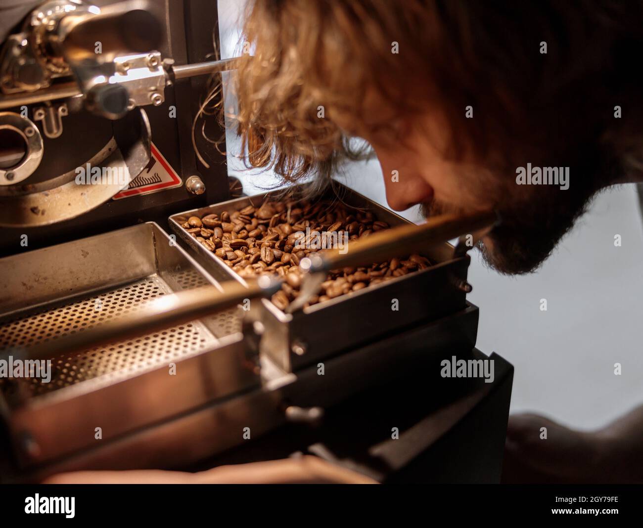 Professional roaster using coffee roasting machine at factory Stock Photo