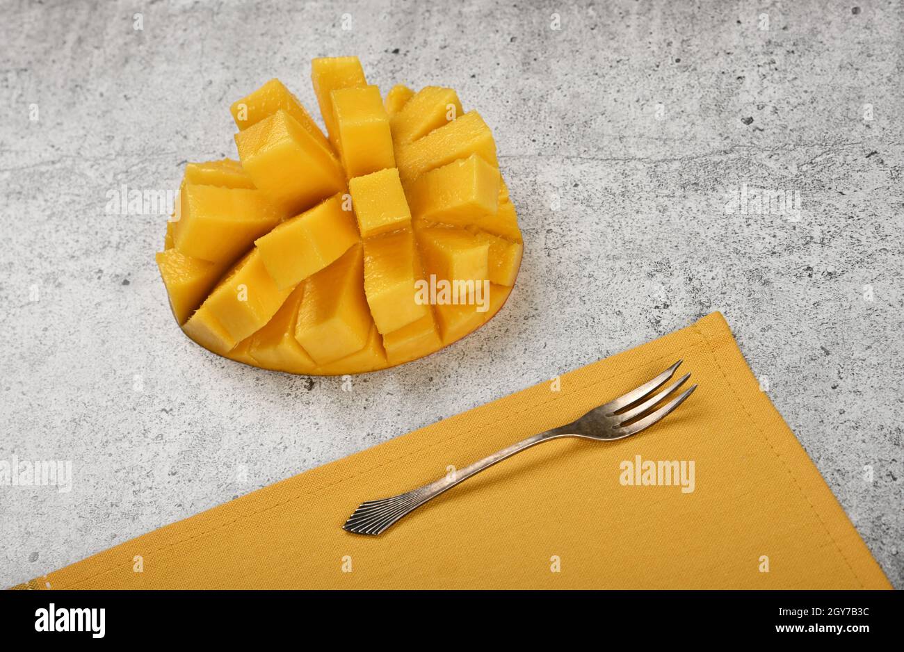 Close up serving fresh ripe cut mango dessert on gray stone table, elevated top view, directly above Stock Photo