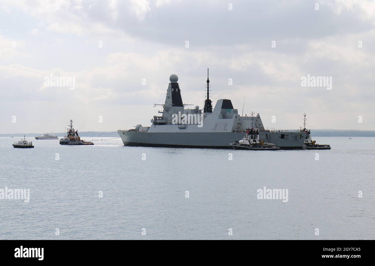 Tugs and the Admiralty pilot vessel guide the Royal Navy Type 45 destroyer HMS DARING into The Solent Stock Photo