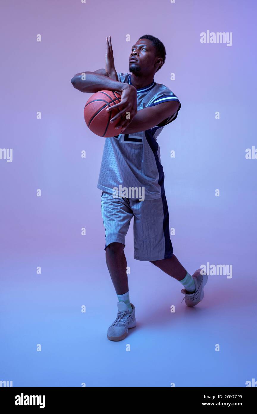 Strong basketball player hand holds ball in studio, neon background