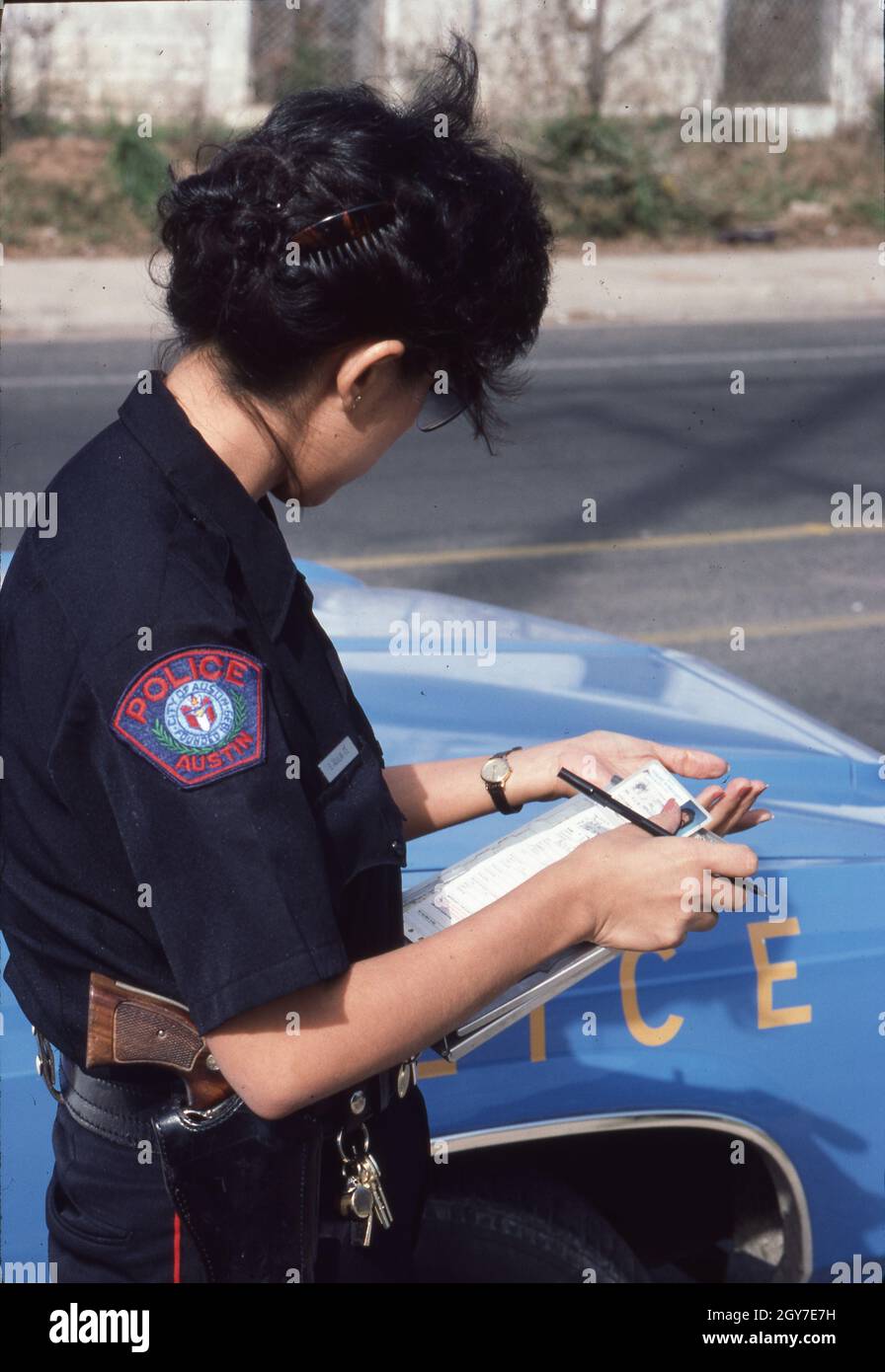 Austin Texas USA, circa 1991: Hispanic female police officer checks driver's license of motorist during traffic stop. ©Bob Daemmrich Stock Photo