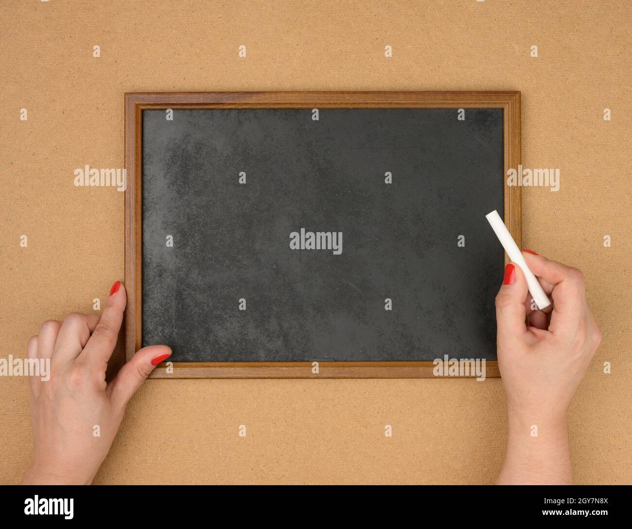 female hands and empty rectangular brown wooden frame on a brown background, copy space Stock Photo