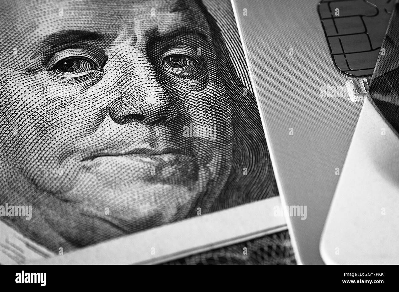 Benjamin Franklin's face on a hundred-dollar bill next to a credit card. Close-up. A hundred-dollar American bill with the eyes of Benjamin Franklin. Stock Photo